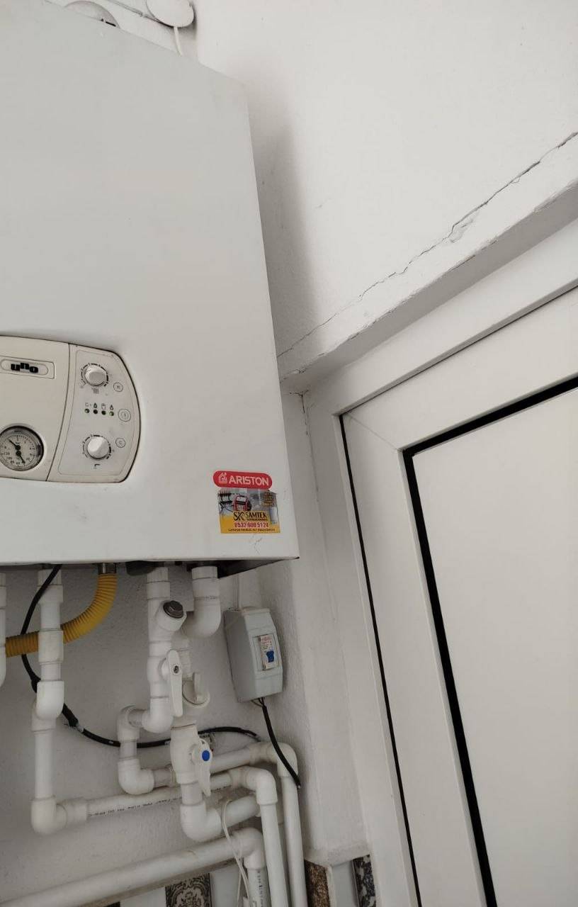 Duvara takılı Ariston kombi, servis etiketi ve altındaki vanalar